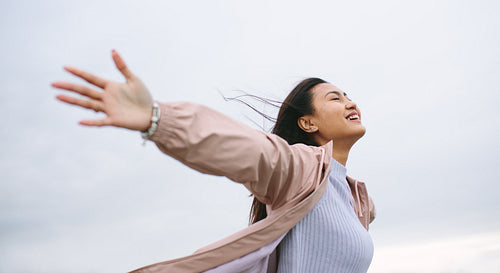 Asian woman enjoying nature standing with open arms