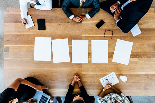 Multi-ethnic business people in meeting with blank pages on table