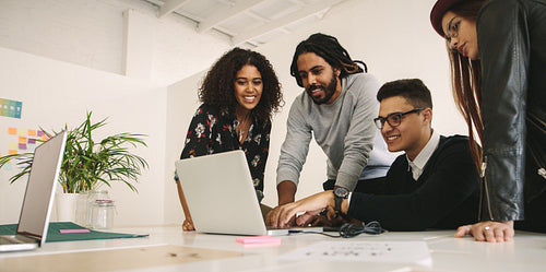 Office mates working together as a team on a computer
