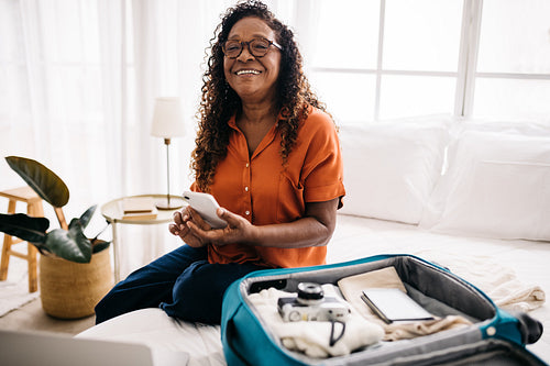 Woman using a travel app on her mobile phone in a hotel room
