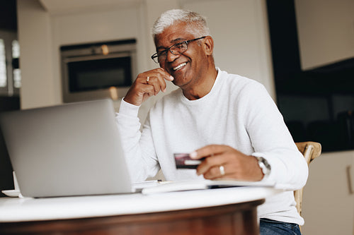 Cheerful senior man shopping online at home
