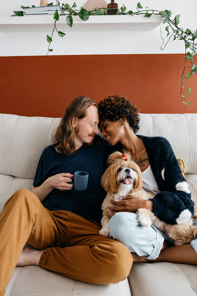 Couple relaxing on sofa with dog and coffee at home