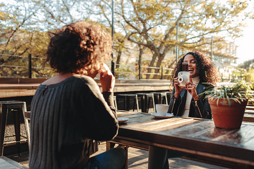 Two women friends drinking coffee and clicking photos