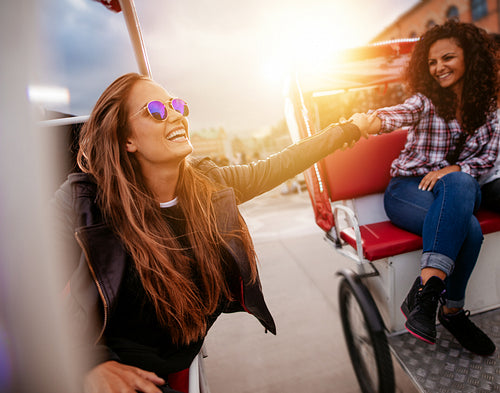 Young women having fun on two tricycles