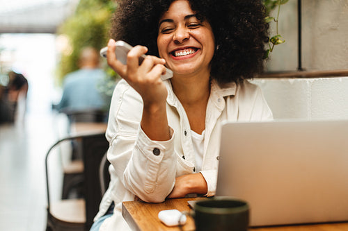 Woman smiling and speaking on a phone call in a coworking space