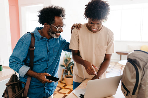 Afro father and son start their happy morning routine together using laptop