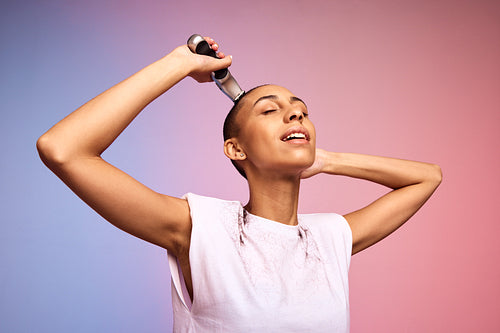 Androgynous female shaving her head