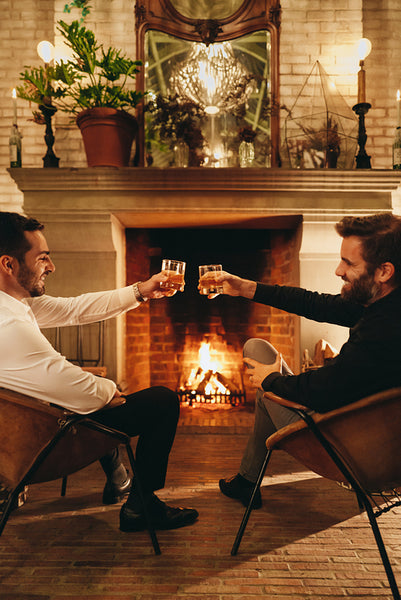 Young men making a toast with whiskey glasses in a hotel
