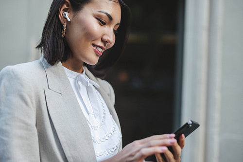 Young business woman playing music on her phone on her way outdoors