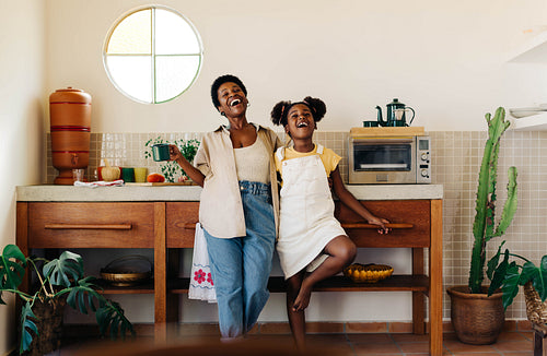 Happy mother and daughter having fun in a Brazilian kitchen