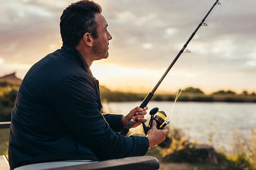Man sitting near a lake with fishing rod