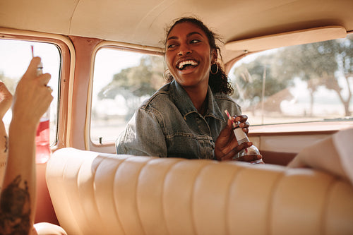 Cheerful woman traveling by car with friends