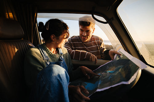 Couple planning road trip with map at sunset