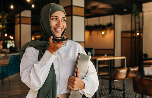 Muslim freelancer taking a phone call in a coffee shop