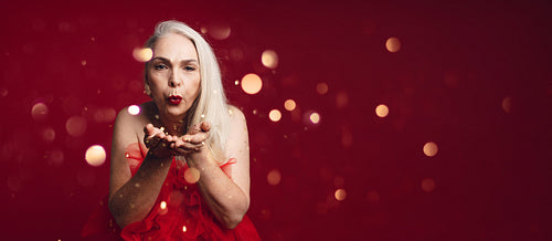 Attractive senior woman blowing glitters
