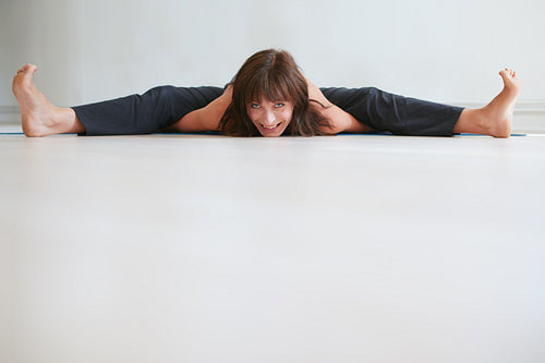 Smiling woman doing splits at gym