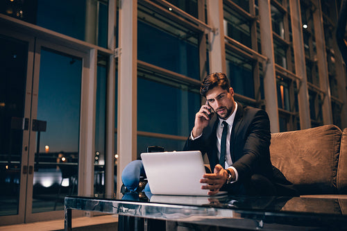 Businessman at airport lounge using laptop and cellphone