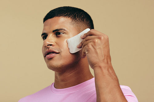 Ancient beauty practice: Male model using a gua sha in a studio