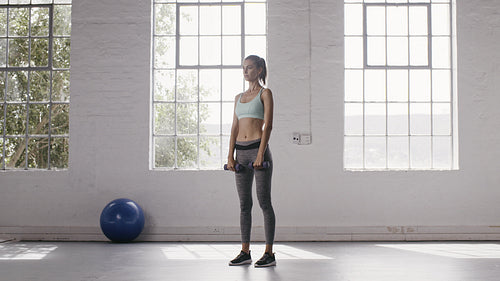 Woman doing dumbbell front raise workout at fitness studio