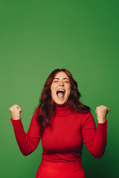 Excited woman screaming and celebrating the Christmas season with joy on a colorful green background