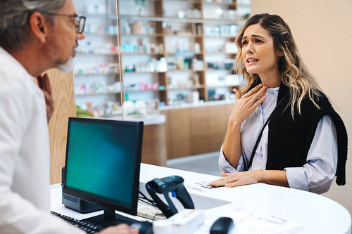 Patient with a cold talking to a pharmacist over the counter
