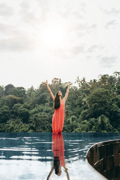 Woman in infinity pool with her hands raised