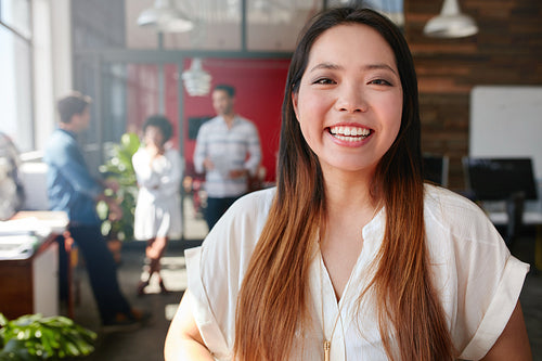 Cheerful young asian woman standing in office 