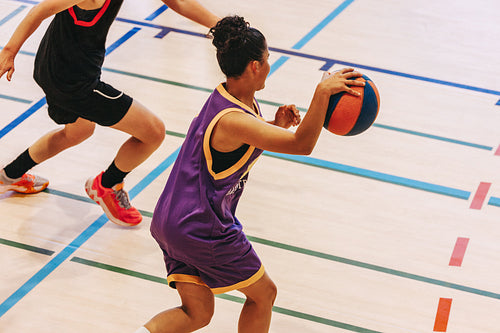 Women playing basketball on an indoor court in a competitive game event
