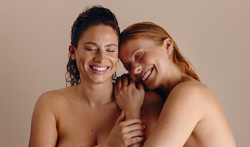 Two women smiling in a warm friendship embrace
