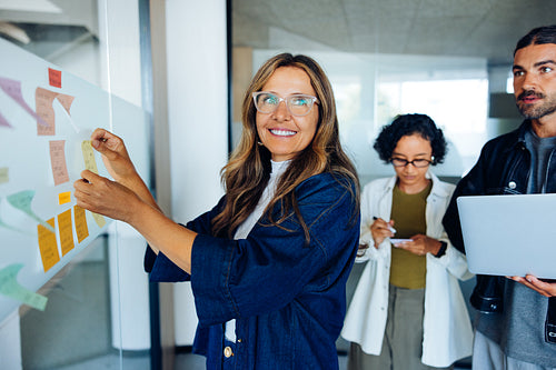Team of professionals pins ideas on glass board