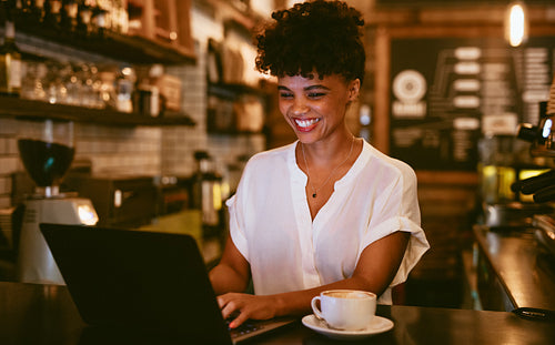 Smiling coffeeshop owner using laptop