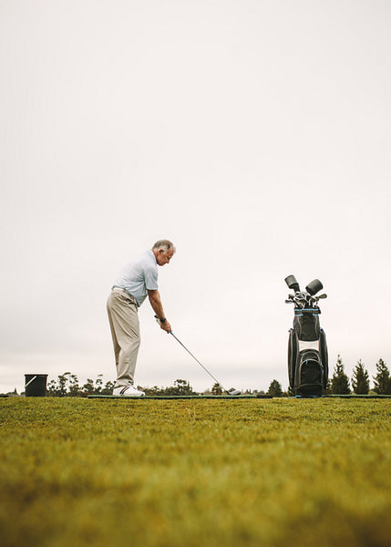 Senior golfer practicing at golf course driving range