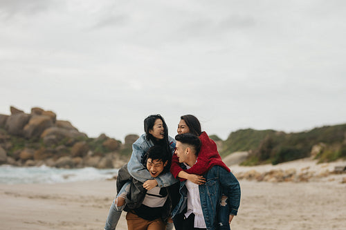 Group of friends piggybacking on the beach