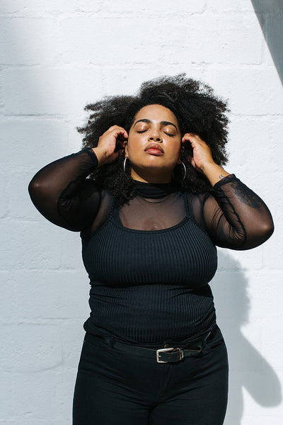 Beautiful woman in stylish outfit standing at a wall