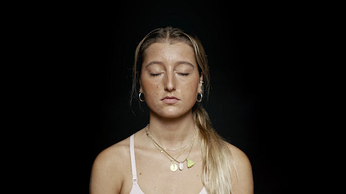 Woman with her eyes closed on black background