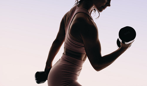 Fit woman training with weights in a studio silhouette