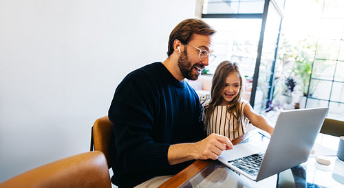 Father and daughter explore together on laptop