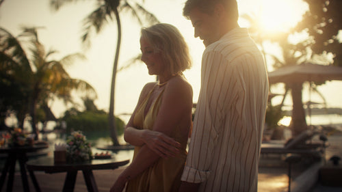 Joyful couple enjoying a romantic moment dancing together at golden hour in a tropical paradise