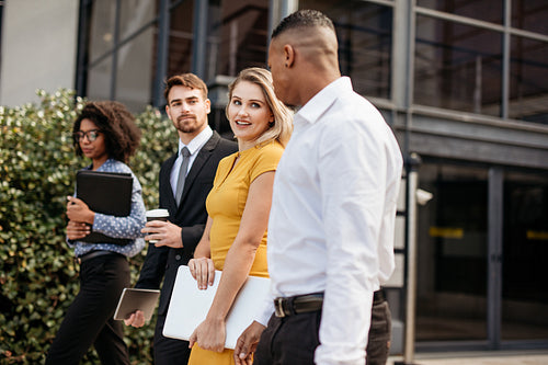 Group of multi-ethnic business people waking outside office building