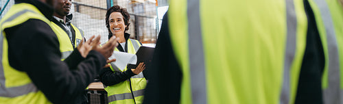 Happy mature woman having a meeting with her team in a warehouse