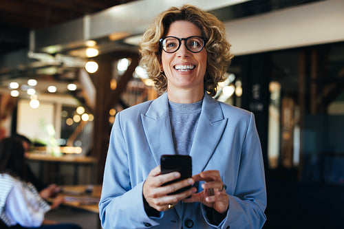 Business woman in a suit using a mobile phone in an office