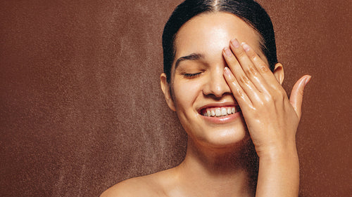 Refreshed and rejuvenated woman smiles under a shower in a studio