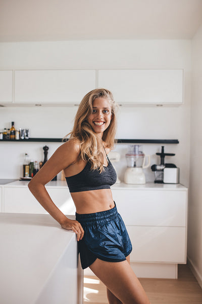 Female standing in kitchen looking happy