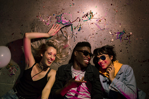 Three friends lying on the floor laughing at a house party