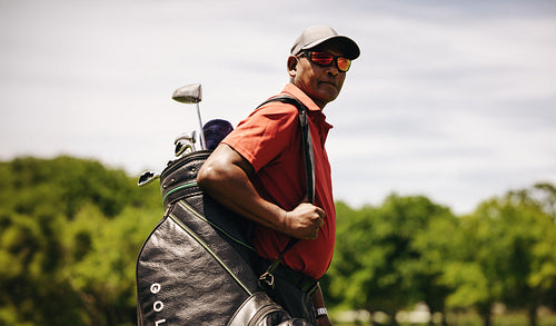 Close-up of a male golfer wearing sunglasses on a sunny golf course day