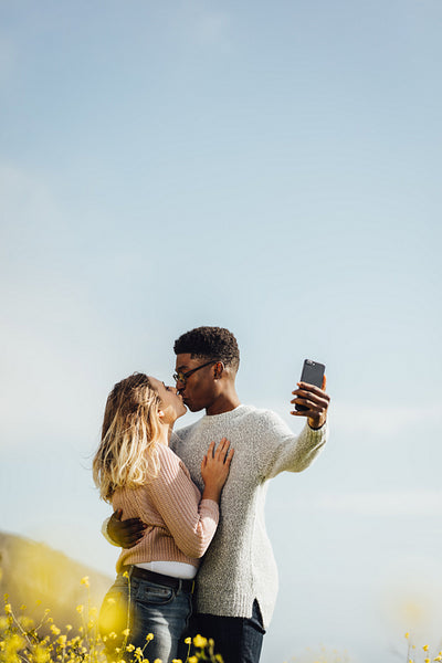 Interracial couple kissing and taking selfie