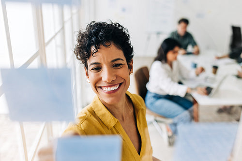 Business woman writing on sticky notes on a glass wall