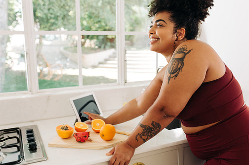 Healthy woman with digital tablet and fruits in kitchen