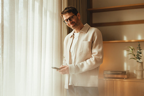 Business owner uses smartphone by the window in a minimalist office