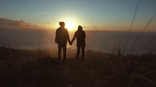 Loving couple on peak looking at sunset